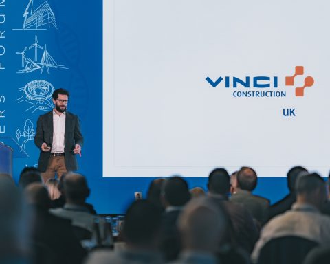 VINCI presentation Speaker presenting to an audience in front of VINCI Construction UK branding