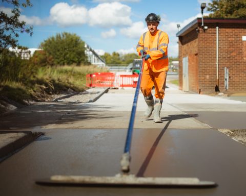 Site surveying Worker in orange high-visibility clothing using surveying equipment on site