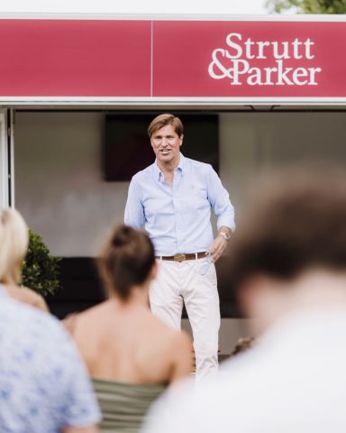 Event speaker Speaker addressing seated guests beneath Strutt & Parker signage