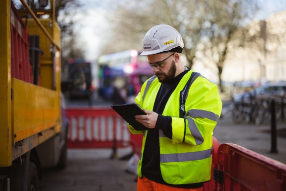 Project checks Construction worker wearing a hard hat checking a tablet outdoors