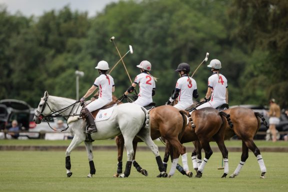 Polo team Four mounted polo players lined up together on the field
