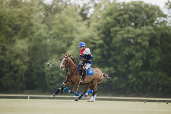 Polo match action Two polo players riding alongside each other on the grass field