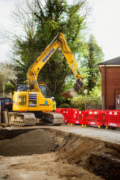 Excavation work Yellow excavator working behind red safety barriers on a construction site